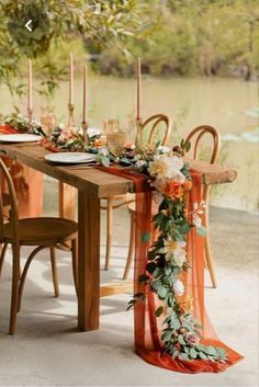 the table is set with an orange runner and floral centerpieces, along with candles