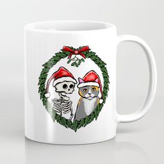 a white coffee mug with a skeleton and cat in a christmas wreath on it's side