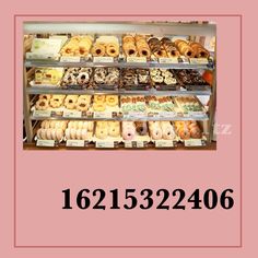 a display case filled with lots of donuts on top of pink paper next to a white frame