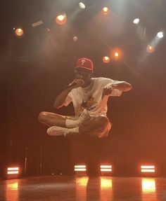 a man jumping in the air on top of a wooden floor with lights behind him