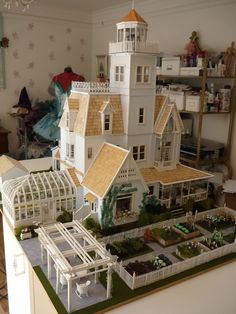 a model of a large white house with lots of plants in the yard and on top of it