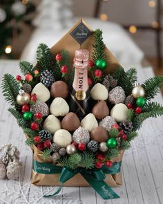 a wine bottle is in the center of a christmas wreath with chocolates and pine cones