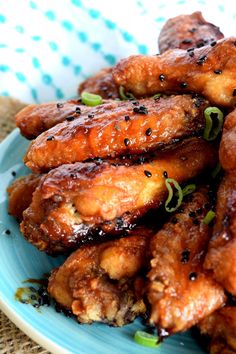 a blue plate topped with chicken wings covered in sesame seeds