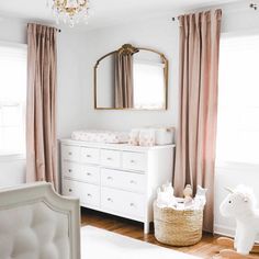 a baby's room with white furniture and pink curtains