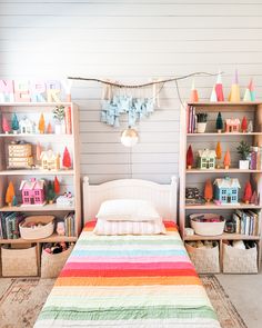 there is a bed in the room with colorful blankets on it and shelves behind it