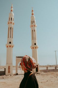 a woman standing in front of two tall white towers