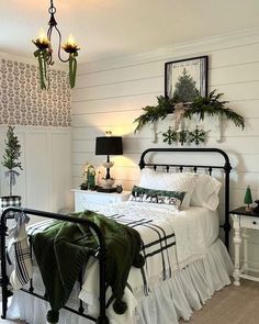 a bedroom with white walls and black iron bedspread, green throw pillows on the bed