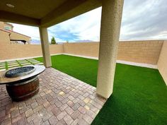 an outdoor patio with grass and brick pavers