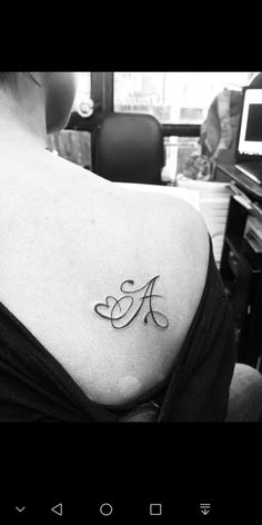 a woman with a tattoo on her shoulder and the letter a in cursive font