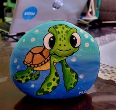 a painted rock with a turtle on it's face and laptop in the background