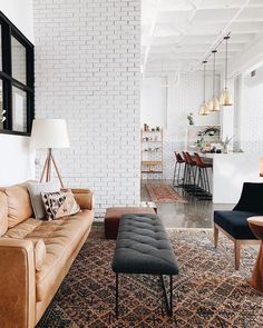 a living room filled with furniture next to a white brick wall and floor covered in rugs