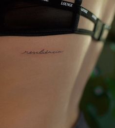 a woman's lower back tattoo with the word forbidden written in cursive writing