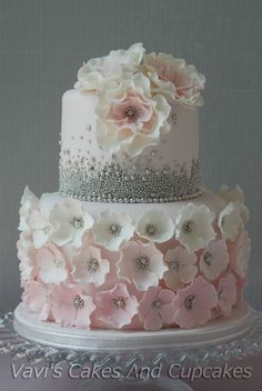 a three tiered wedding cake with flowers on the top and silver trimmings