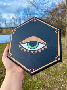 a hand holding up a small box with an eye painted on it