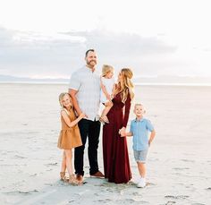 a family standing on the beach with their two children