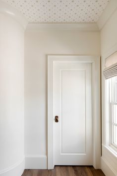 an empty room with a white door and wooden floors