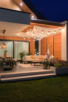 an outdoor patio with lights strung over it and furniture on the steps leading up to the deck