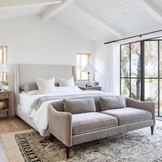 a large white bed sitting next to a window in a bedroom