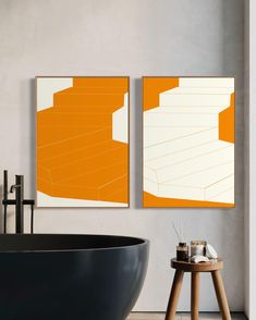 two orange and white paintings hanging on the wall next to a bathtub in a bathroom