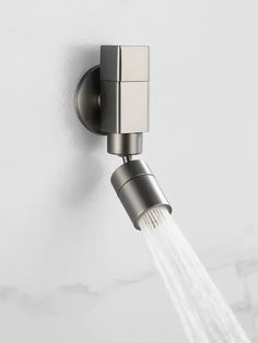 a faucet with water coming out of it on a white wall next to a shower head