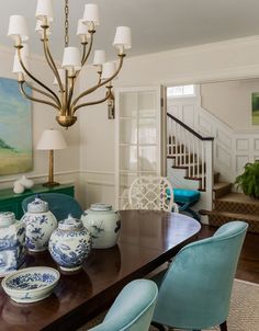 a dining room table with blue and white china on it, next to a staircase