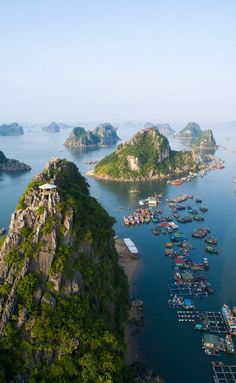 an aerial view of many boats in the water near mountains and islands with trees on them