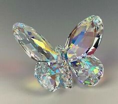 a butterfly shaped crystal object sitting on top of a white table next to a gray background