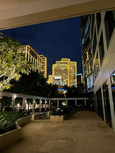 the hotel is lit up at night in front of other buildings and trees, along with potted plants