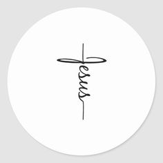 a cross with the word jesus written in cursive ink on a white round sticker