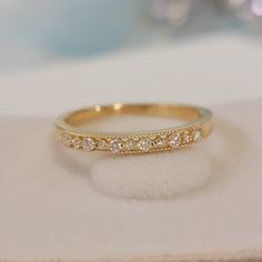 a gold wedding band with five diamonds on it sitting on top of a white cloth