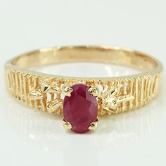 a yellow gold ring with a red stone