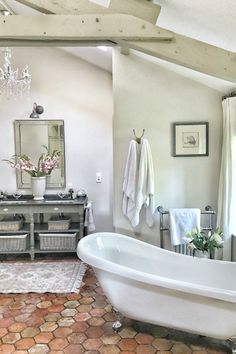 a bathroom with a tub, chandelier and rug on the floor in front of it