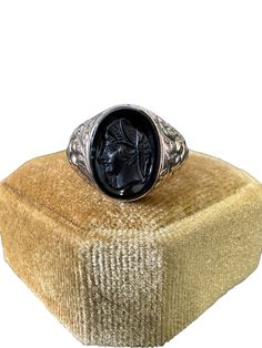 Lovely vintage 10k rose gold onyx cameo ring with a detailed intaglio of a soldier, circa 1907! The bezel set black gemstone cameo is oval cut. Unique piece of fine vintage jewelry, over 100 years old! ERA - Circa 1907 / Edwardian Era METAL / MATERIAL - 10k rose gold, onyx MARKINGS / HISTORY - RFB Oct 19-07 CONDITION - Good vintage condition. Piece has been professionally cleaned and lightly polished. The carved cameo is intact and secure in setting. Small chips on stone. Age appropriate wear to metal including scratch to back of ring head. Amazing Edwardian era ring! SIZE / MEASUREMENTS - Size: 8 1/2, Ring head height: 15 mm, Band: tapers to 3 mm, Weight: 3.8 grams (Ring can be resized within reason by our local jeweler or likely yours. Please contact us prior to purchasing if you are int Black Victorian Signet Ring Collectible, Black Round Cameo Jewelry, Victorian Style Black Signet Ring Collectible, Vintage Black Cameo Ring, Vintage Black Carved Rings, Black Cameo Ring As Gift, Black Cameo Ring For Gift, Black Intaglio Jewelry As A Gift, Vintage Black Carved Jewelry