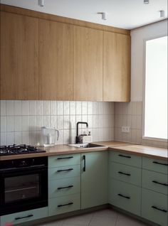 a kitchen with green cabinets and white tiled walls