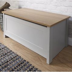 a wooden bench sitting on top of a hard wood floor next to a white brick wall