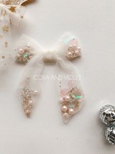 three bows with pearls and sequins on them next to a disco ball ornament