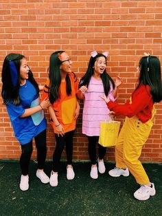 three girls in costumes standing next to a brick wall