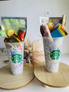 two starbucks cups are sitting on top of a wooden tray with various items in them