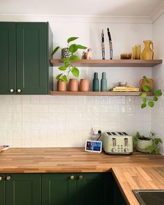 a kitchen with green cabinets and wooden counter tops