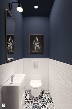 a white toilet sitting next to a sink in a bathroom under a painting on the wall