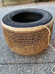 an old tire is sitting on the ground next to a roped potted planter