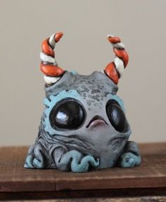 a small ceramic figurine with horns on it's head sitting on top of a wooden table