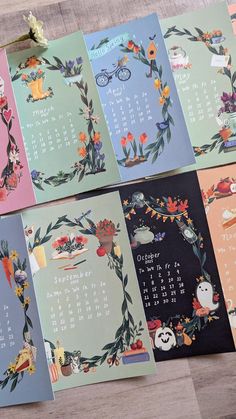 four calendars with different designs on them sitting on a wooden table next to each other