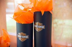 two black harley davidson beer cans with orange tissue paper on them sitting in front of a window