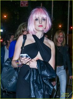 a woman with pink hair is carrying a black bag