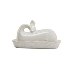 a white ceramic object with a cat on it's back sitting in a boat