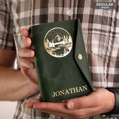 a man holding a green book with the word jonathan written on it in gold lettering