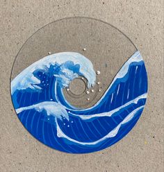 a blue and white painted circular object with waves on it