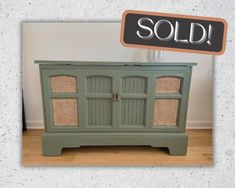 an old green cabinet with wicker doors and sold sign on it's side