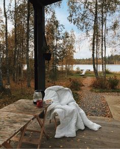 a picnic table with a blanket on it next to a lake